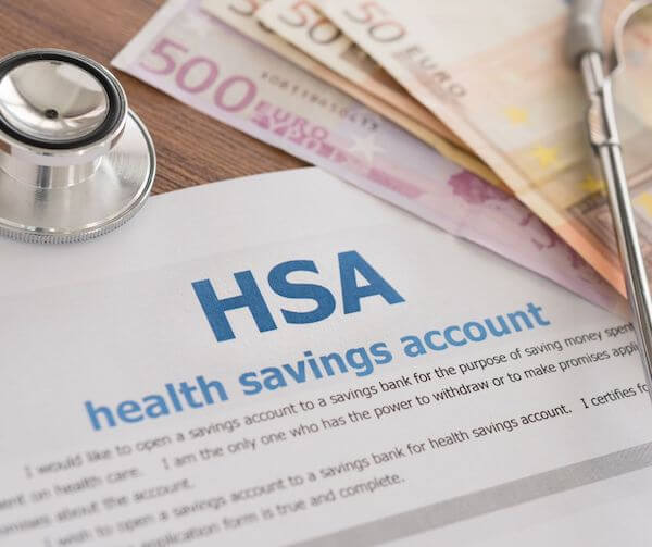 a pen and money on top of a piece of paper health savings accounts