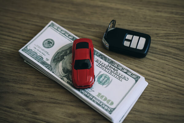 a toy car on a stack of dollars buying or leasing your vehicle